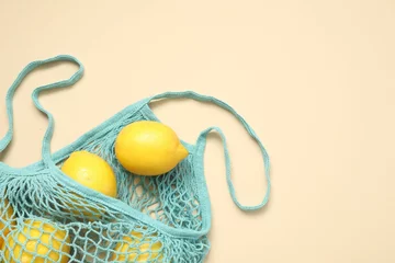 Fotobehang String bag with fresh lemons on beige background, top view. Space for text © New Africa