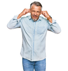 Fototapeta premium Middle age grey-haired man wearing casual clothes smiling pulling ears with fingers, funny gesture. audition problem