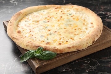 Delicious cheese pizza and basil on black marble table, closeup