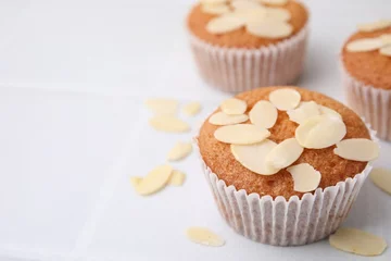 Foto op Plexiglas Muffins with fresh almond flakes on white tiled table, closeup. Space for text © New Africa