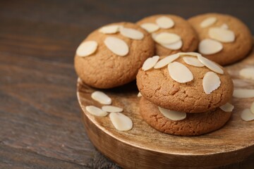 Cookies with fresh almond flakes on wooden table, closeup. Space for text