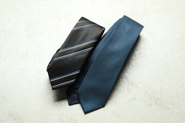 Two neckties on light textured table, top view