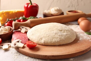 Pizza dough, products and rolling pin on gray table, closeup