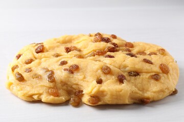 Fresh dough with raisins on white textured table, closeup