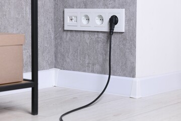 Naklejka premium Power sockets and electric plug on grey wall