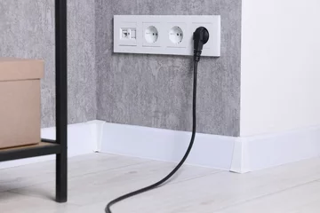 Rolgordijnen Power sockets and electric plug on grey wall © New Africa