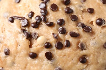Raw dough with chocolate chips as background, top view