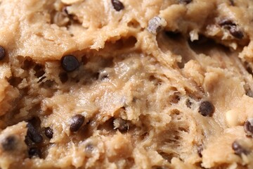 Raw dough with chocolate chips as background, closeup