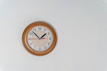 Clock Hanging on Wall in Room. time at 1 hour and 50 minutes. white wall. Round clock