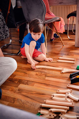 A young child is fully immersed in playing with a colorful wooden train set on a gleaming hardwood...
