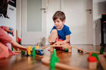 A young child deeply focused on playing with a wooden train set, constructing his own little world on the living room floor, showcasing early learning and creativity