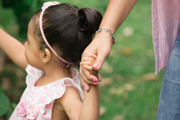 Family holding children hands walking through a park together 