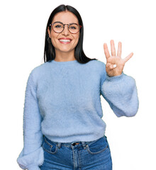 Young hispanic woman wearing casual clothes and glasses showing and pointing up with fingers number...
