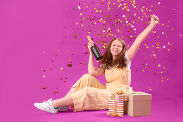 Beautiful woman with Birthday gifts, bottle of champagne and falling confetti on purple background
