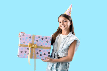 Happy little girl with Birthday gift box on blue background