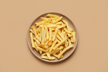 Plate with golden french fries on beige background