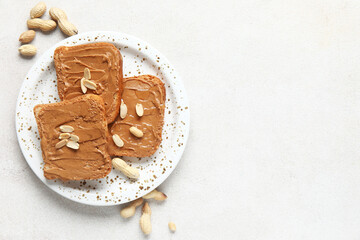 Plate of toasts with peanut butter and nuts on white background