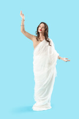Beautiful young Indian woman in sari on blue background