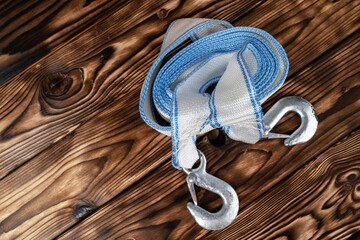 car tow rope with hooks. A rolled-up blue and white rope lying on a wooden table.