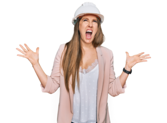 Young blonde woman wearing architect hardhat crazy and mad shouting and yelling with aggressive expression and arms raised. frustration concept.