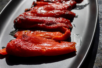 Roasted red bell peppers on a black platter as a side dish