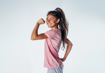 strong young girl showing her muscles, wearing pink t-shirt, isolated on white 