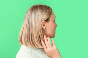 Woman with multiple ear piercing on green background