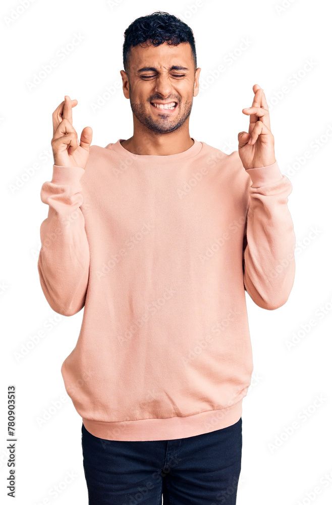 Poster young hispanic man wearing casual clothes gesturing finger crossed smiling with hope and eyes closed