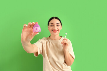 Beautiful young happy woman with dental floss and toothbrush on green background