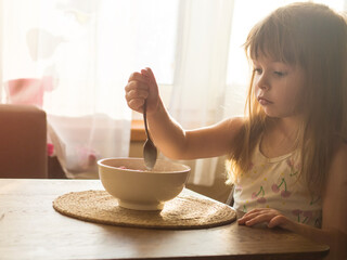 child having breakfast with corn flakes and milk