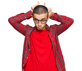 Hispanic young man wearing casual clothes doing funny gesture with finger over head as bull horns
