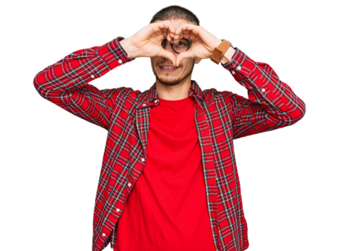 Hispanic young man wearing casual clothes doing heart shape with hand and fingers smiling looking through sign