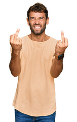 Fototapeta premium Handsome young man with beard wearing casual tshirt showing middle finger doing fuck you bad expression, provocation and rude attitude. screaming excited