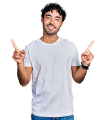 Hispanic young man with beard wearing casual white t shirt smiling confident pointing with fingers...