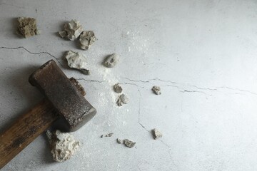 One sledgehammer and broken stones on grey textured background, flat lay. Space for text