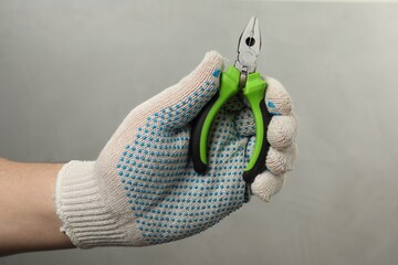 Man with combination pliers on grey background, closeup