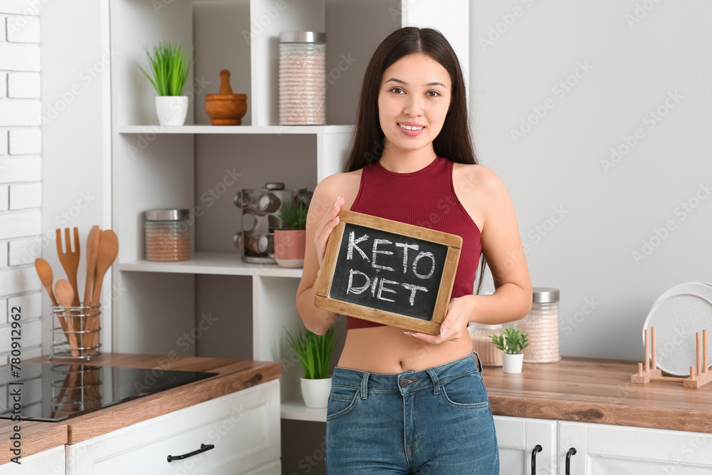 Wall mural beautiful young happy asian woman holding chalkboard with text keto diet at home