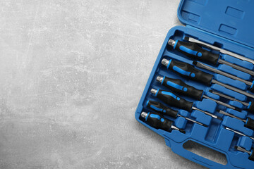 Set of screwdrivers in open toolbox on grey textured table, top view. Space for text