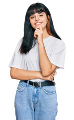 Young hispanic girl wearing casual clothes looking confident at the camera with smile with crossed arms and hand raised on chin. thinking positive.