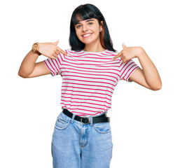 Young hispanic girl wearing casual clothes looking confident with smile on face, pointing oneself...