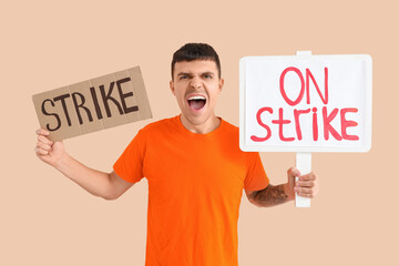 Protesting young man with placards on beige background. Strike concept