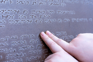 The hand of a blind man reads a Braille text, touching the relief. High quality photo