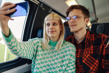 Travelers traveling by train and taking selfies during journey.