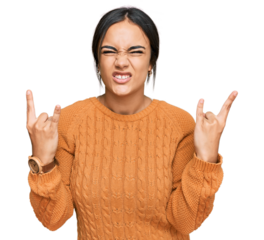 Young brunette woman wearing casual winter sweater shouting with crazy expression doing rock symbol with hands up. music star. heavy concept.