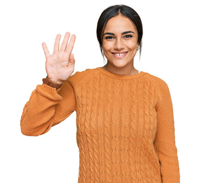 Young brunette woman wearing casual winter sweater showing and pointing up with fingers number four while smiling confident and happy.