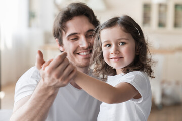 Cute small girl kid child daughter dancing with his young father at home, spending family time...