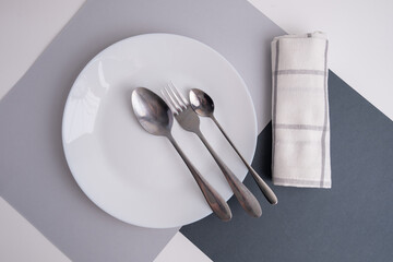 White empty plates and cutlery on a napkin on a white table. Top view of an empty dish. Banner for...