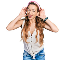 Naklejka premium Young caucasian woman wearing casual style with sleeveless shirt trying to hear both hands on ear gesture, curious for gossip. hearing problem, deaf