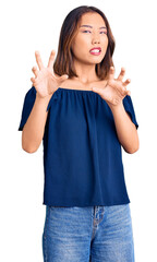 Young beautiful chinese girl wearing casual clothes disgusted expression, displeased and fearful doing disgust face because aversion reaction. with hands raised