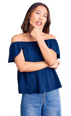 Young beautiful chinese girl wearing casual clothes looking confident at the camera smiling with crossed arms and hand raised on chin. thinking positive.